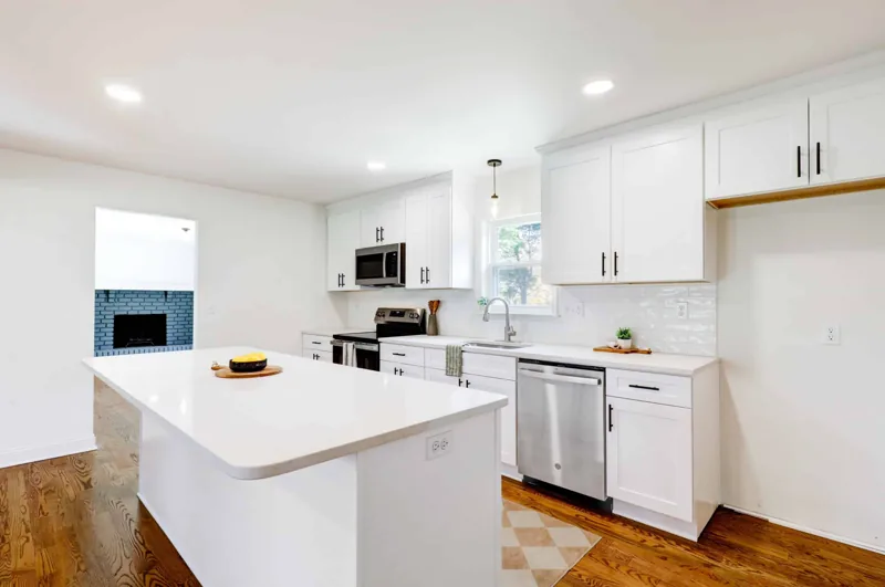 White shaker kitchen with island, black hardware and light countertops