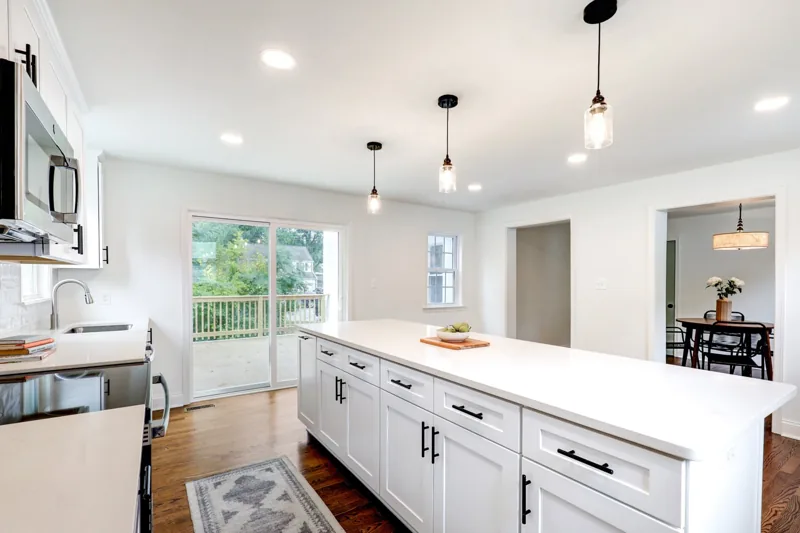 White kitchen island with farmhouse sink and black pendant lights