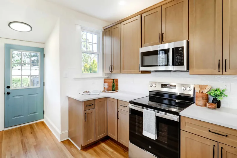 Natural wood shaker cabinets with black hardware and light stone countertops