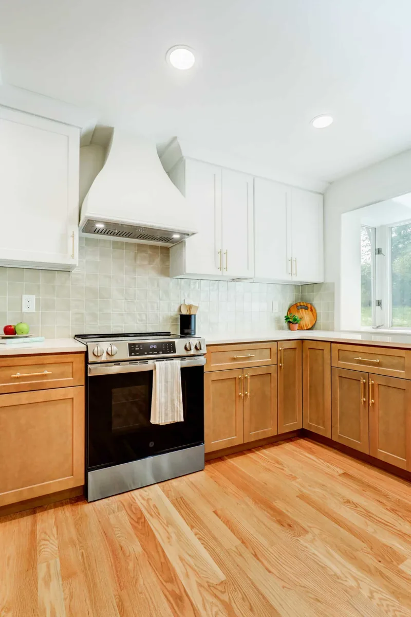 White upper cabinets and natural wood lower cabinets beside a kitchen range