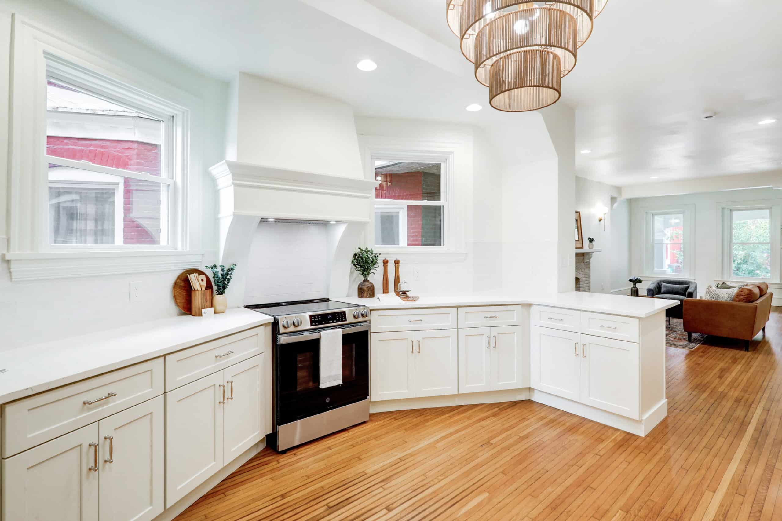 White kitchen with an island, pendant lights and wood flooring