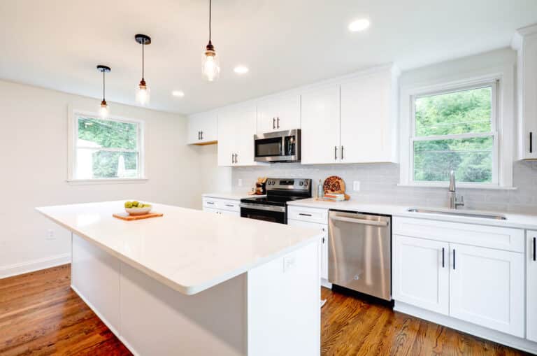 White kitchen with an island, pendant lights and perimeter appliances