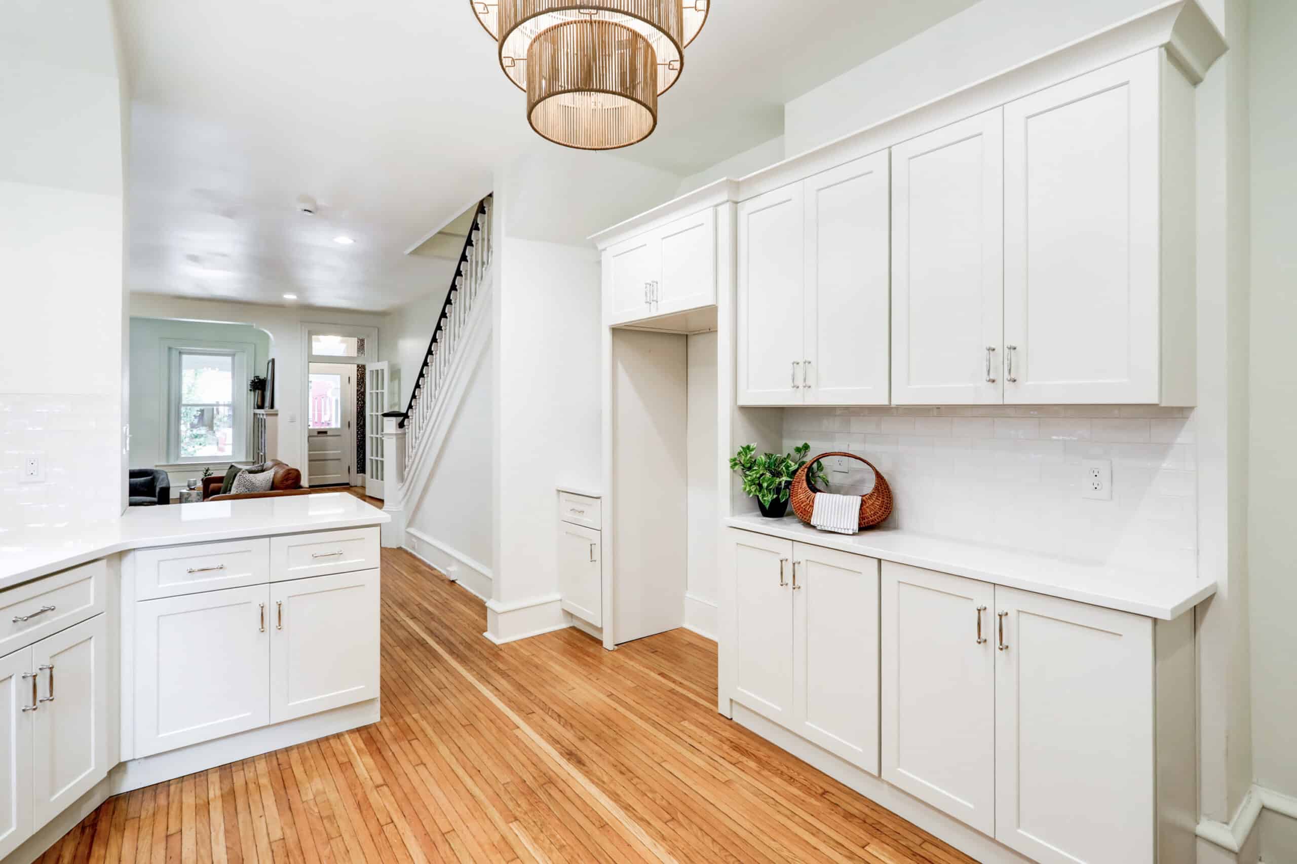 White kitchen cabinet run with a microwave, wood flooring and an adjacent doorway