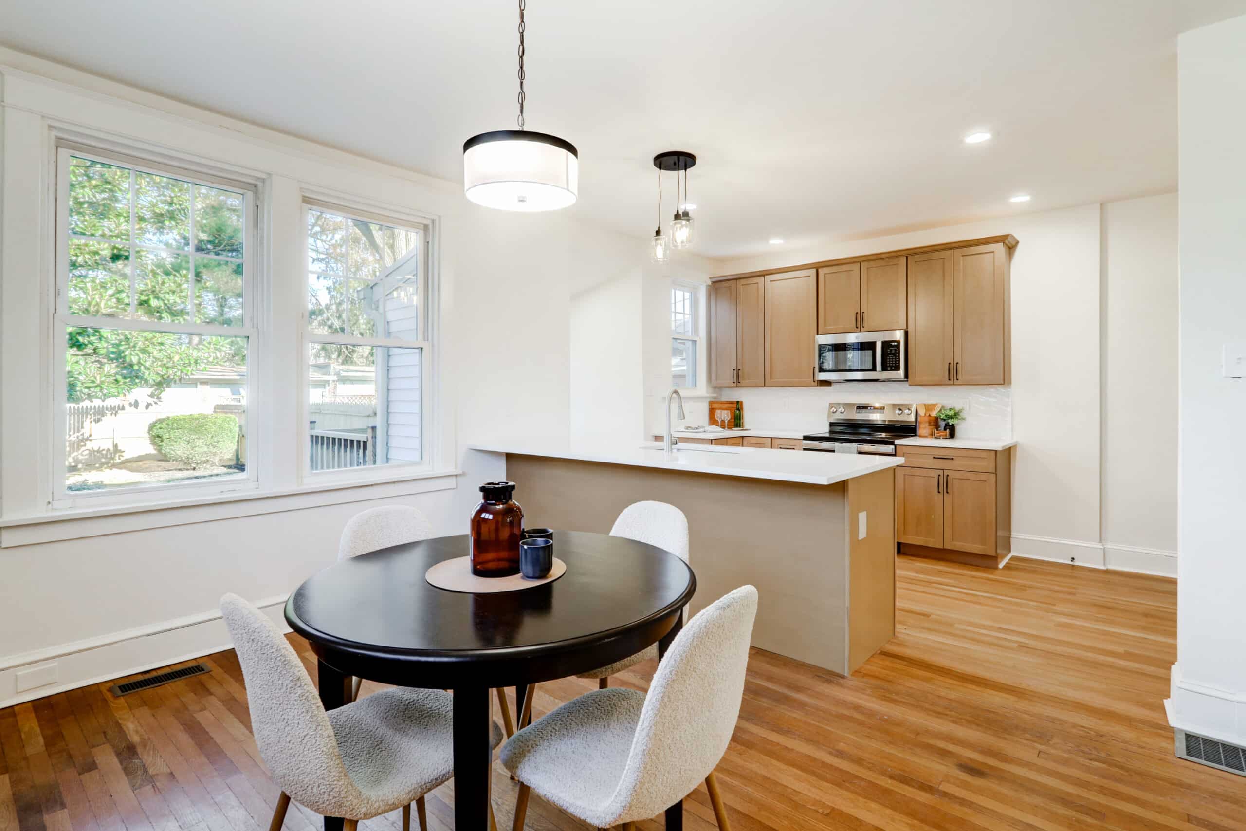 Natural wood kitchen cabinets and island seen from a dining area with a round table