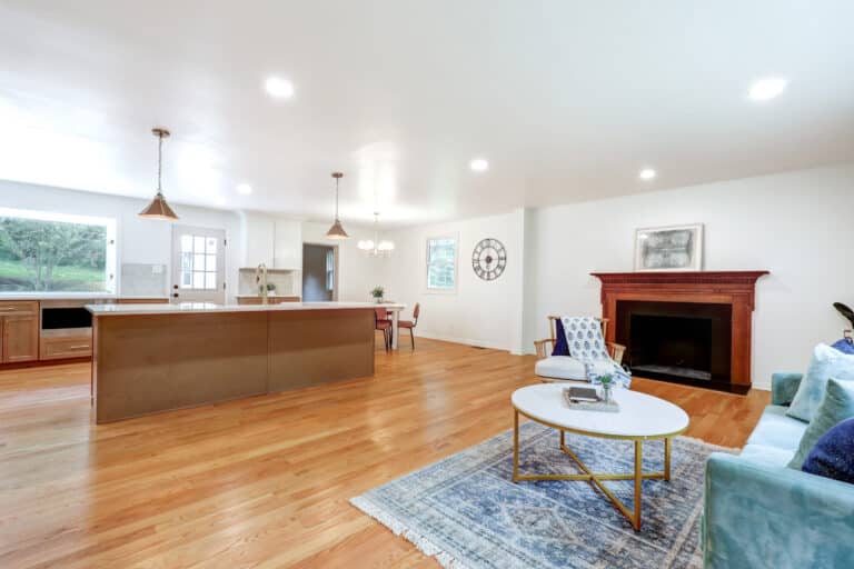 Open kitchen adjoining a living room with seating and a fireplace