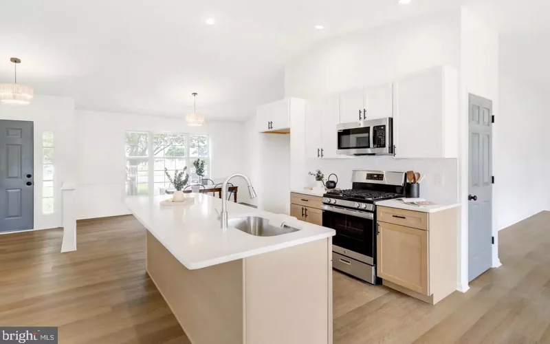 Natural wood kitchen island with a sink, white upper cabinets and a stainless steel range in New Freedom.
