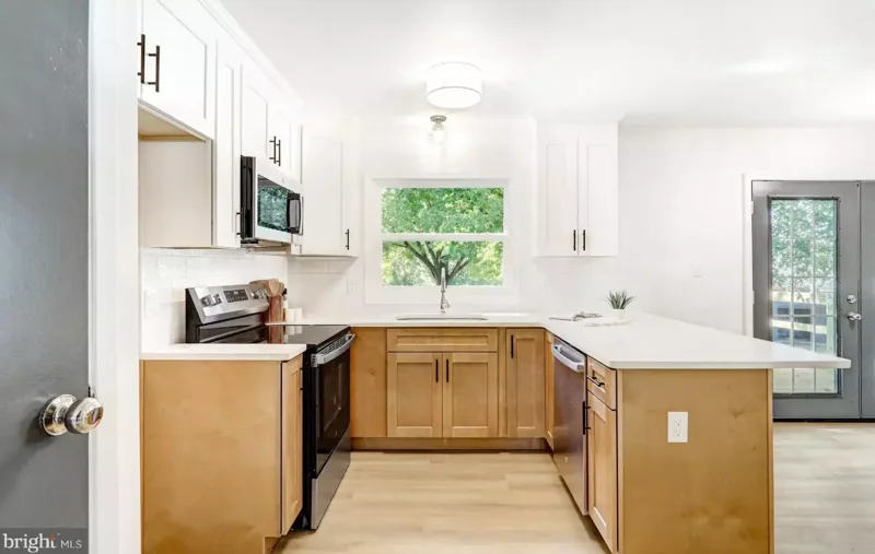 White upper cabinets and natural wood lower cabinets around a light countertop in a Lancaster kitchen.